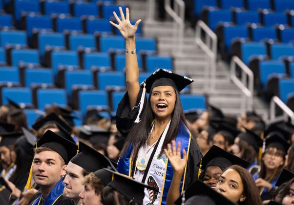 Graduating student waves from the crowd in Pauley Pavilion