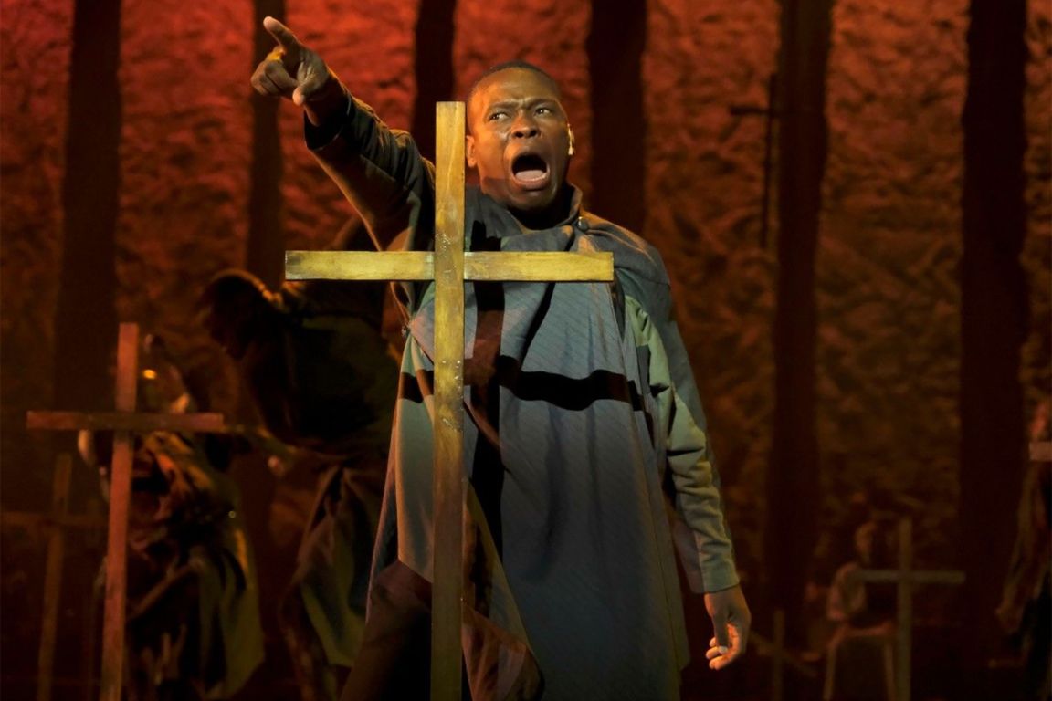 A performer points among a set of crosses in a graveyard