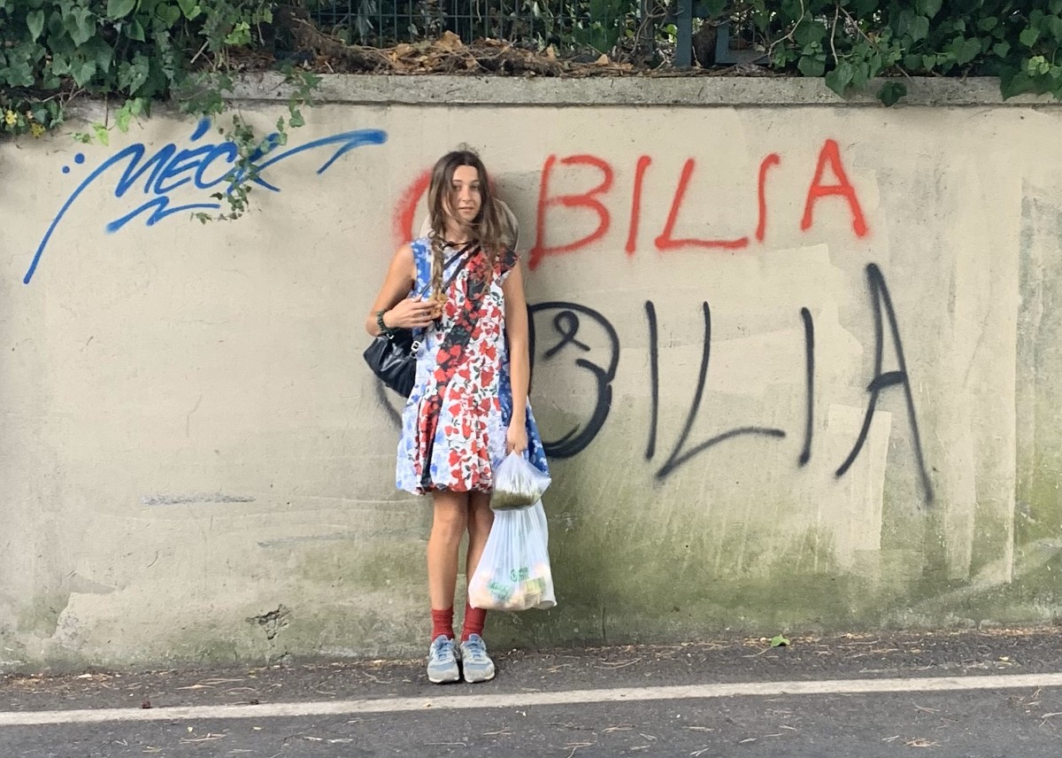 Elya Aboutboul-Bilia stands against a concrete wall 