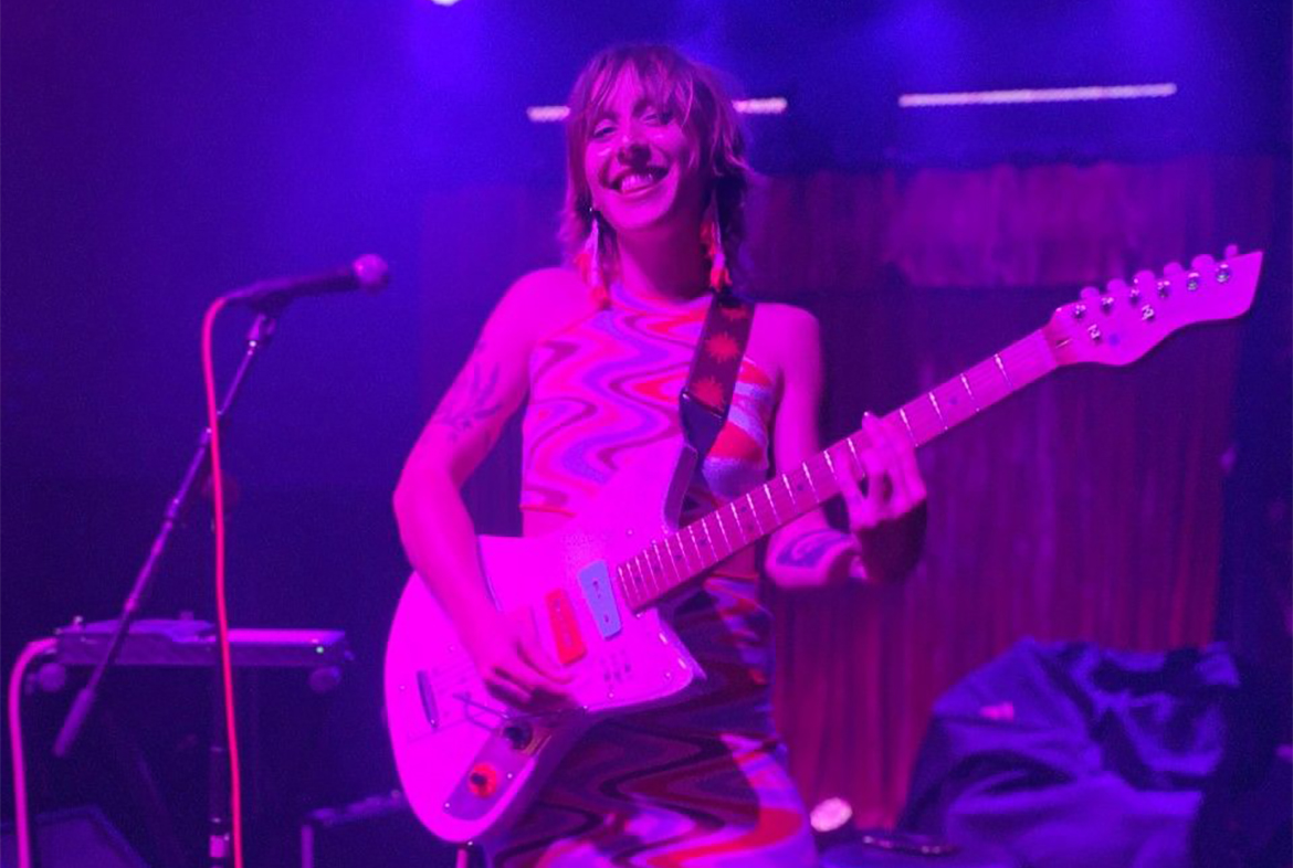 Jasmine Bailey playing guitar under pink lights