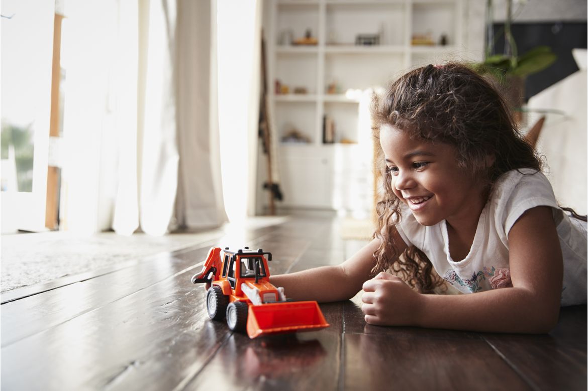 Girl lying on floor playing with red truck