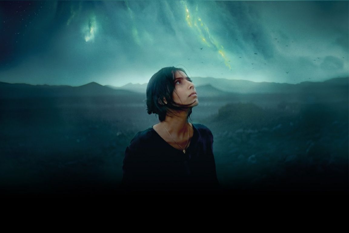 A still from the science fiction film “Animalia” showing a woman looking up at the sky against a background of storm clouds