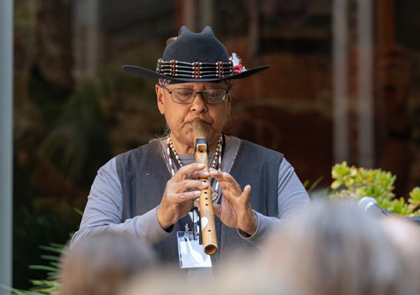 Gabrieleno/Tongva elder Michael Whitehorse Aviles wearing hat and playing flute