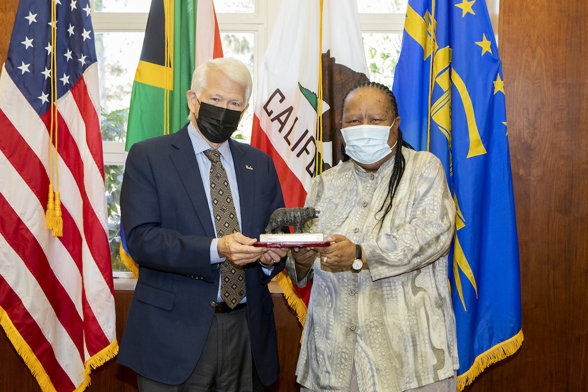 Chancellor Gene Block stands next to Grace Naledi Mandisa Pandor, South Africa’s minister of international relations and cooperation. Both are wearing face masks, with flags in background. 2022.