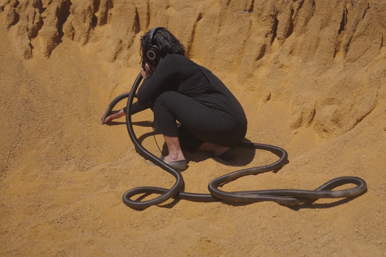 Woman with headphones sticking tube in sand