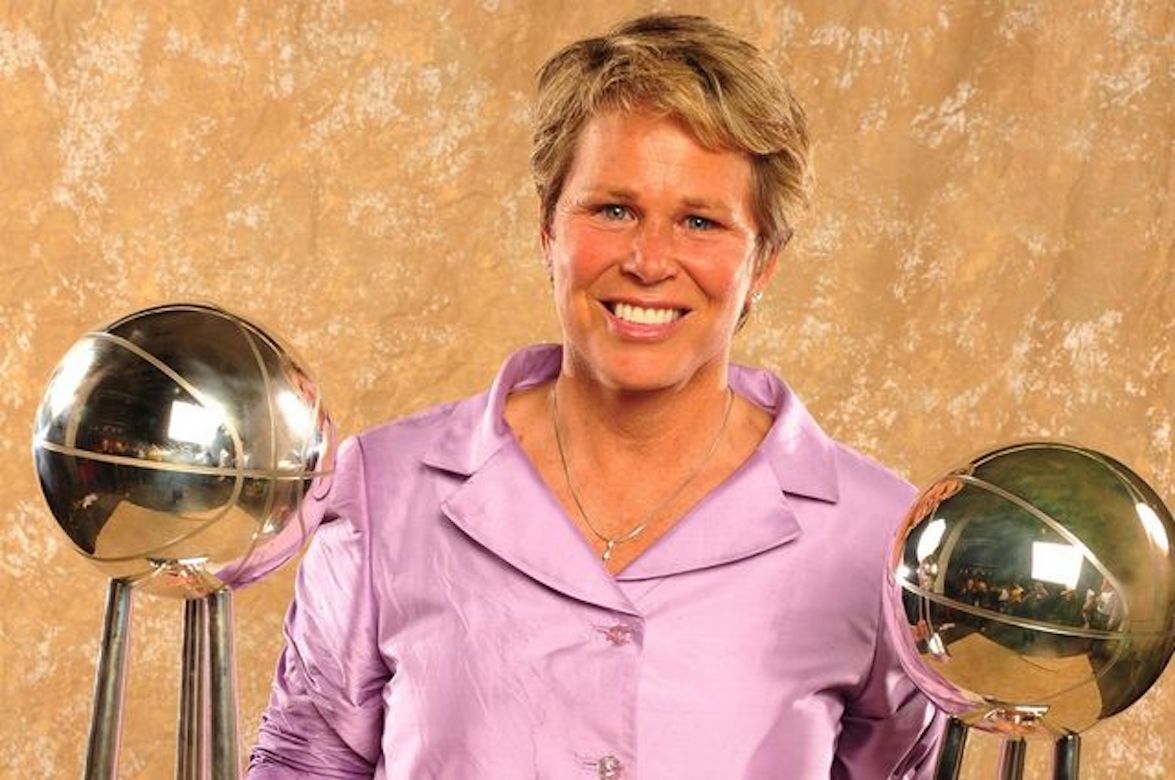 Ann Meyers Drysdale in between two basketball trophies