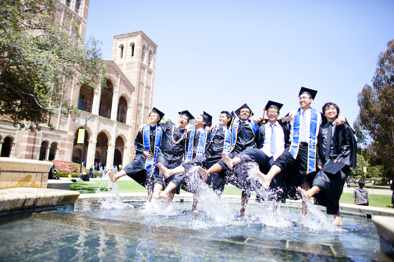 Shapiro Fountain: Eight graduating students in commencement regalia splash their feet in the fountain.