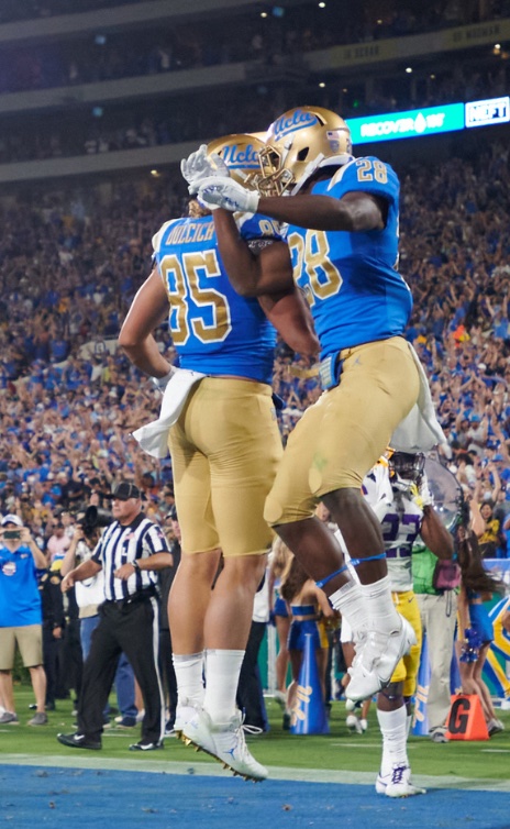 Two UCLA football players jumping up in endzone