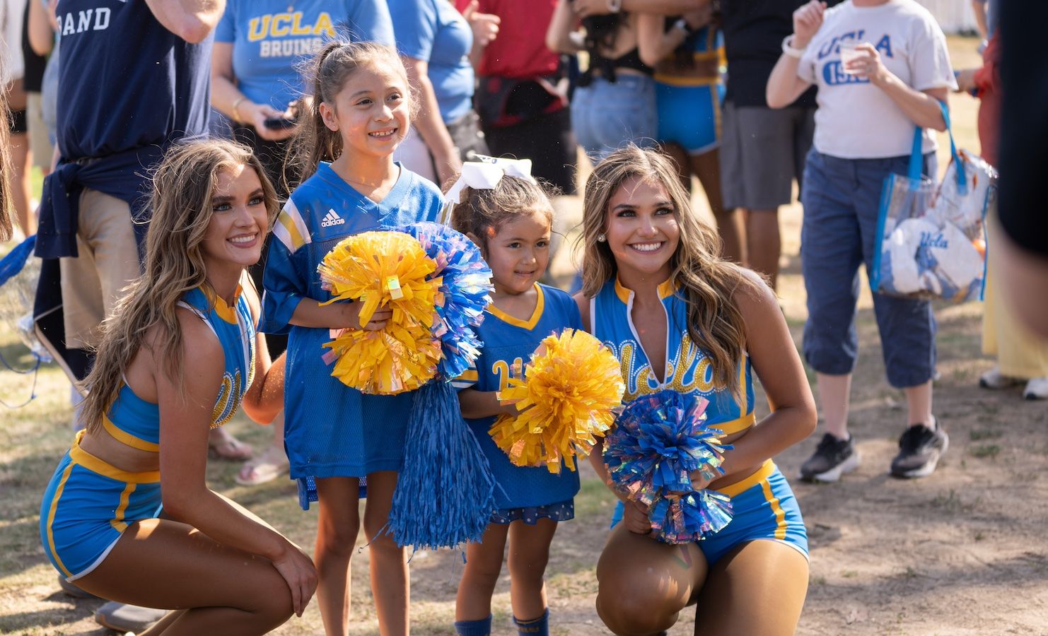 UCLA cheerleaders pose with young fans at the Rose Bowl before the game against Indiana, Sept. 14, 2024.