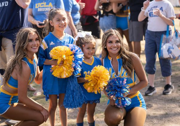 UCLA cheerleaders pose with young fans at the Rose Bowl before the game against Indiana, Sept. 14, 2024.