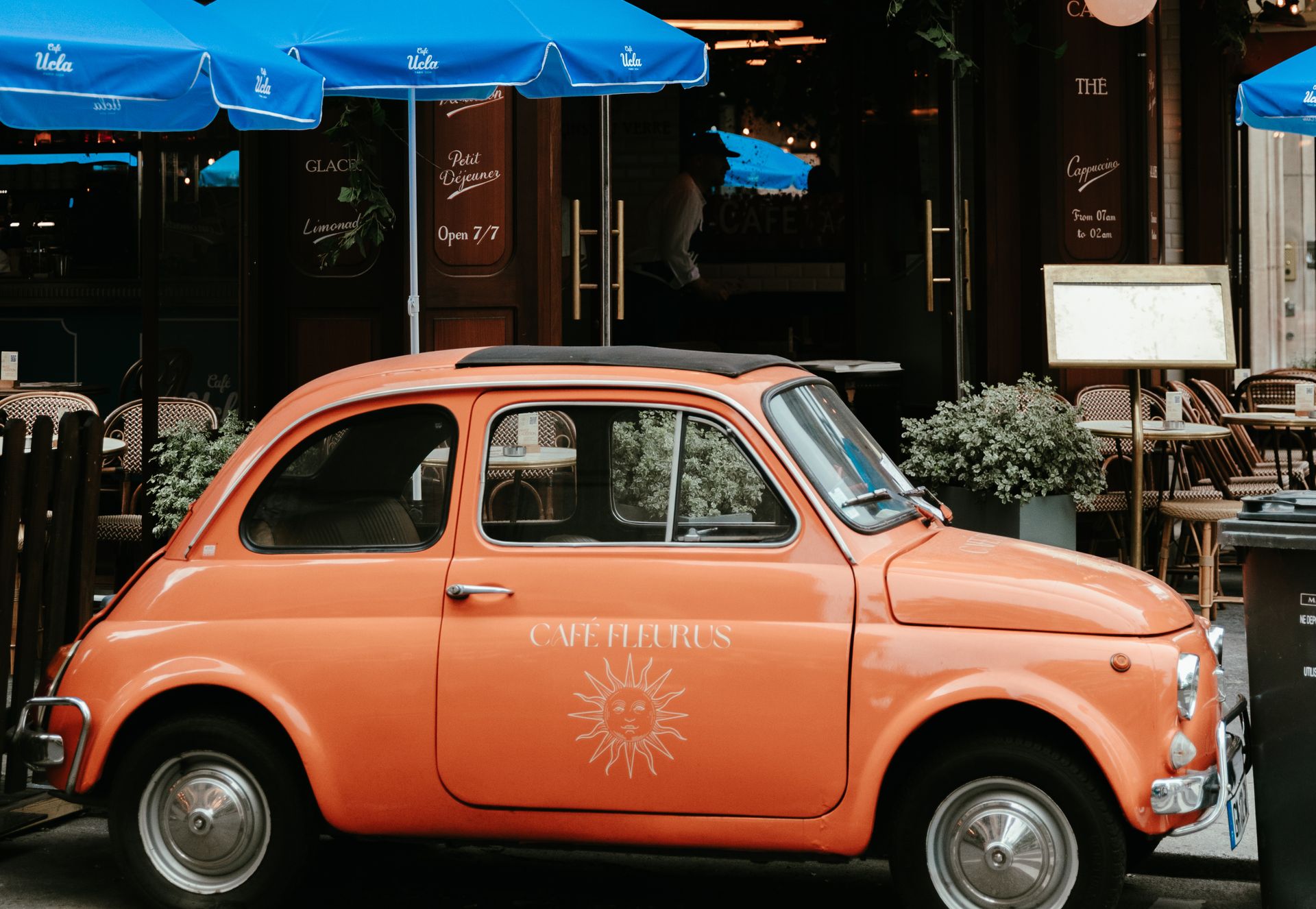 Orange vintage car with Café Fleurus logo on passenger door