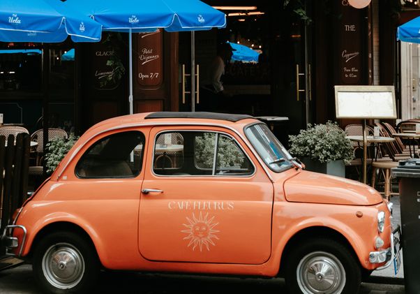 Orange vintage car with Café Fleurus logo on passenger door