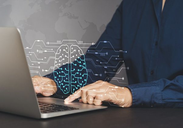 Photo of person using laptop (showing hands and chest), with a graphic of a brain overlaid