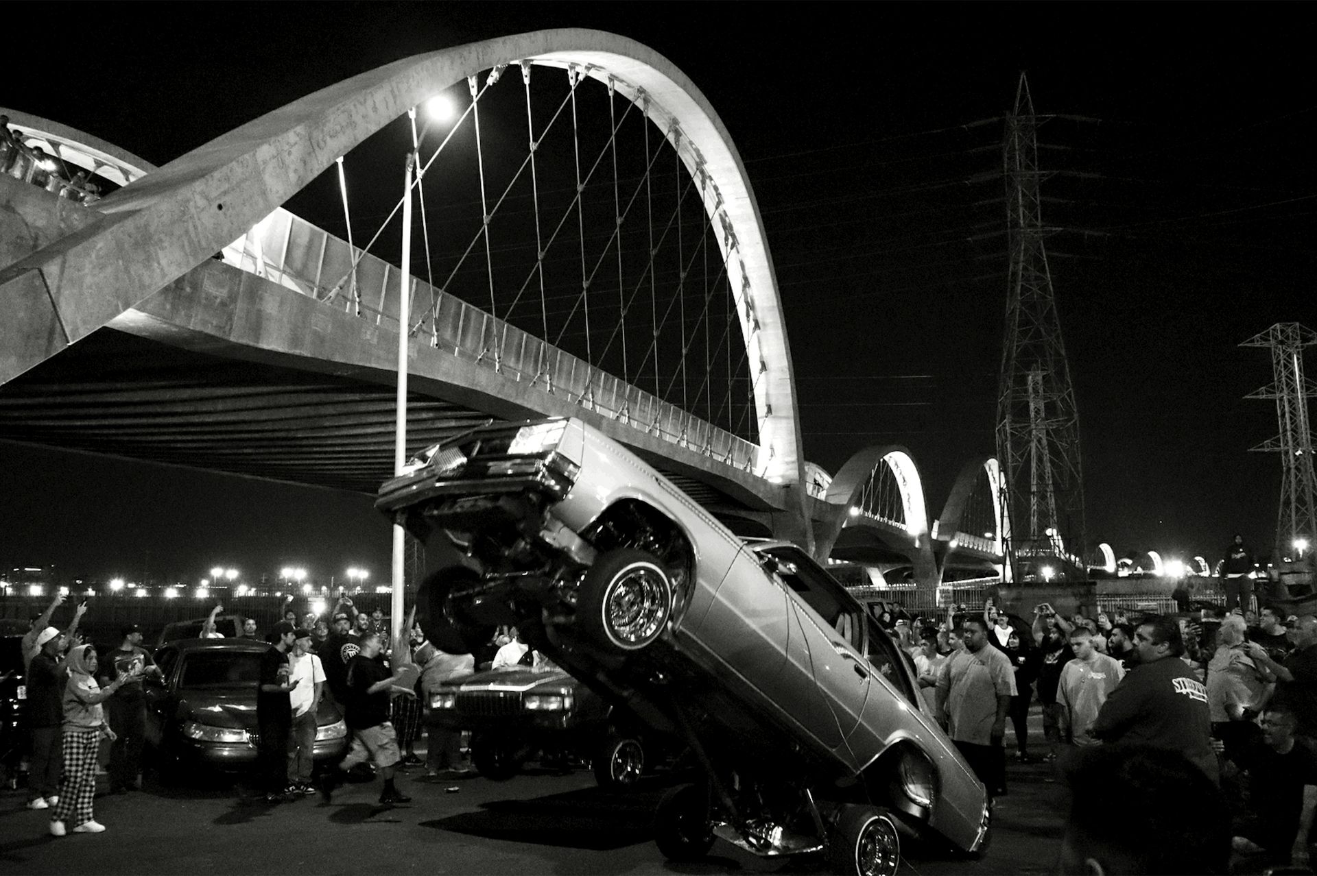 Black-and-white shot of lowrider popping a wheelie near Sixth Street Bridge 