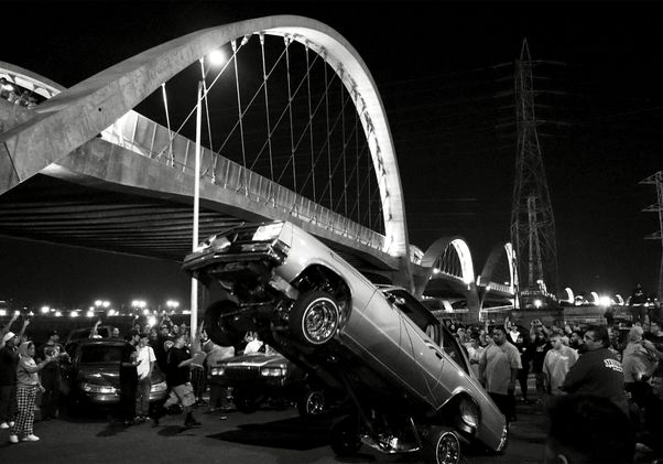 Black-and-white shot of lowrider popping a wheelie near Sixth Street Bridge 