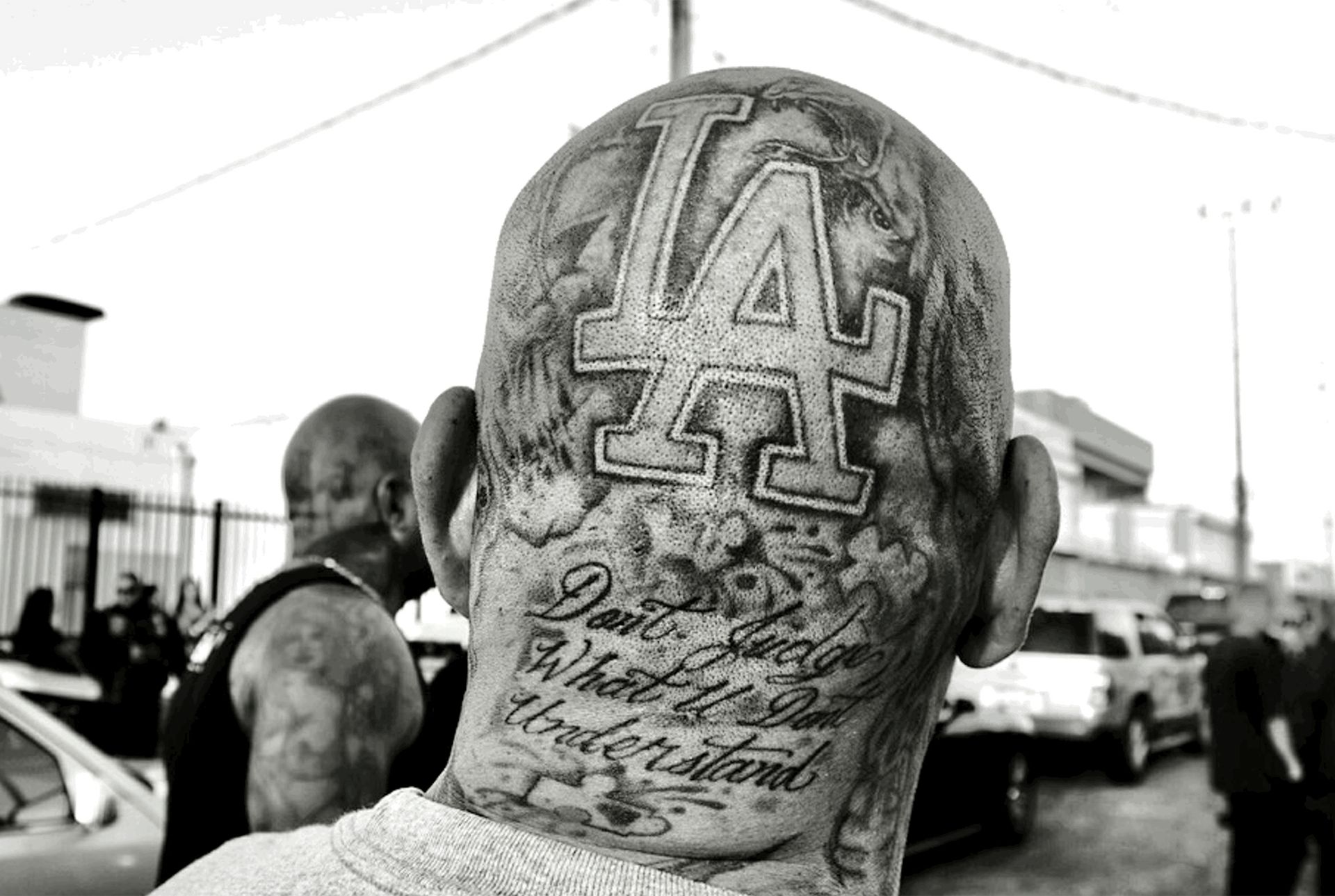 Black-and-white shot of tattoo on back of man’s head reads: “LA Don’t judge what u don’t understand”