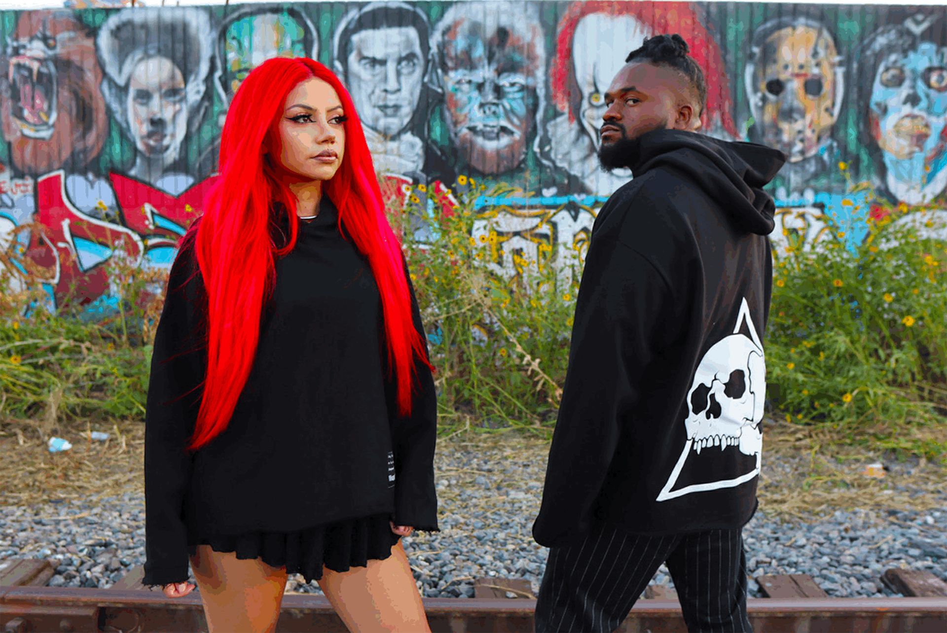 Two people posing in front of graffitied background
