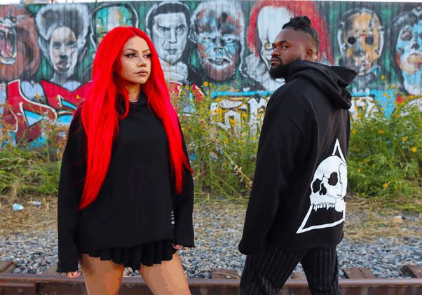 Two people posing in front of graffitied background