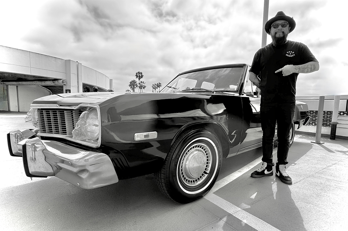 Erick Zerecero, wearing black, standing next to a classic car