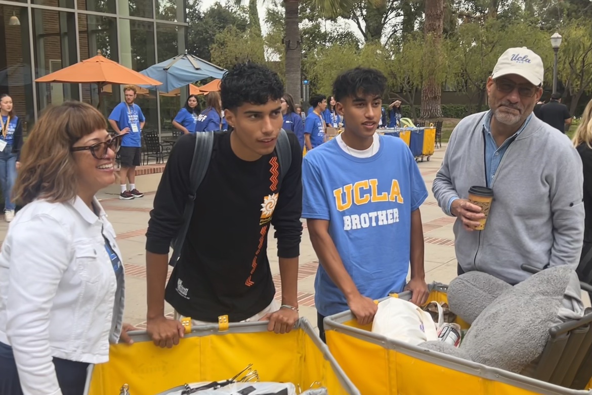 Dean of the social sciences division Abel Valenzuela, far left, helps move his son Milan, a first-year student, into the residence halls. With them are Milan’s brother Miles and mother Sophia. All are standing in front of yellow push-baskets.
