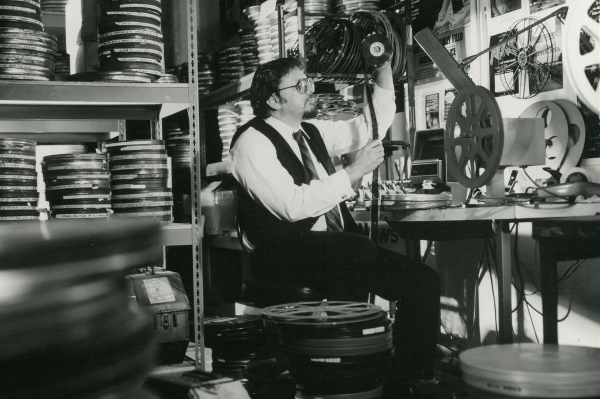 Robert Rosen sitting at a desk surrounded by film reels