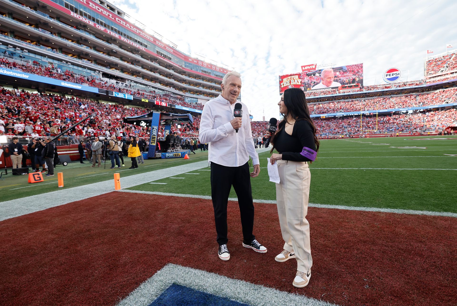 Lindsey Pallares speaking with Joe Montana on football field