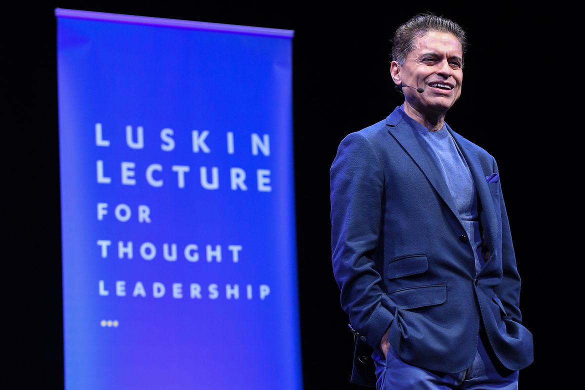 Fareed Zakaria on stage in blue jacket with “Luskin Lecture for Thought Leadership” in background