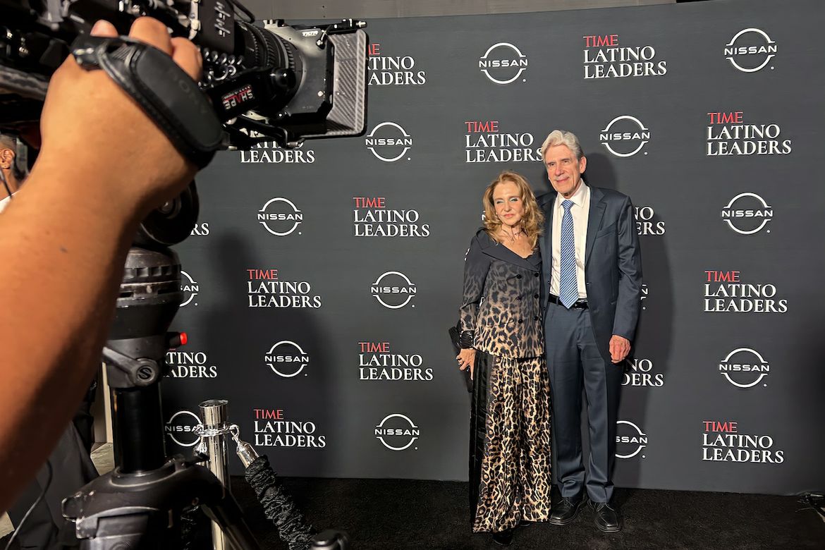 Wide shot of Julio Frenk (right) and Felicia Knaul (center) with camera and hand in foreground