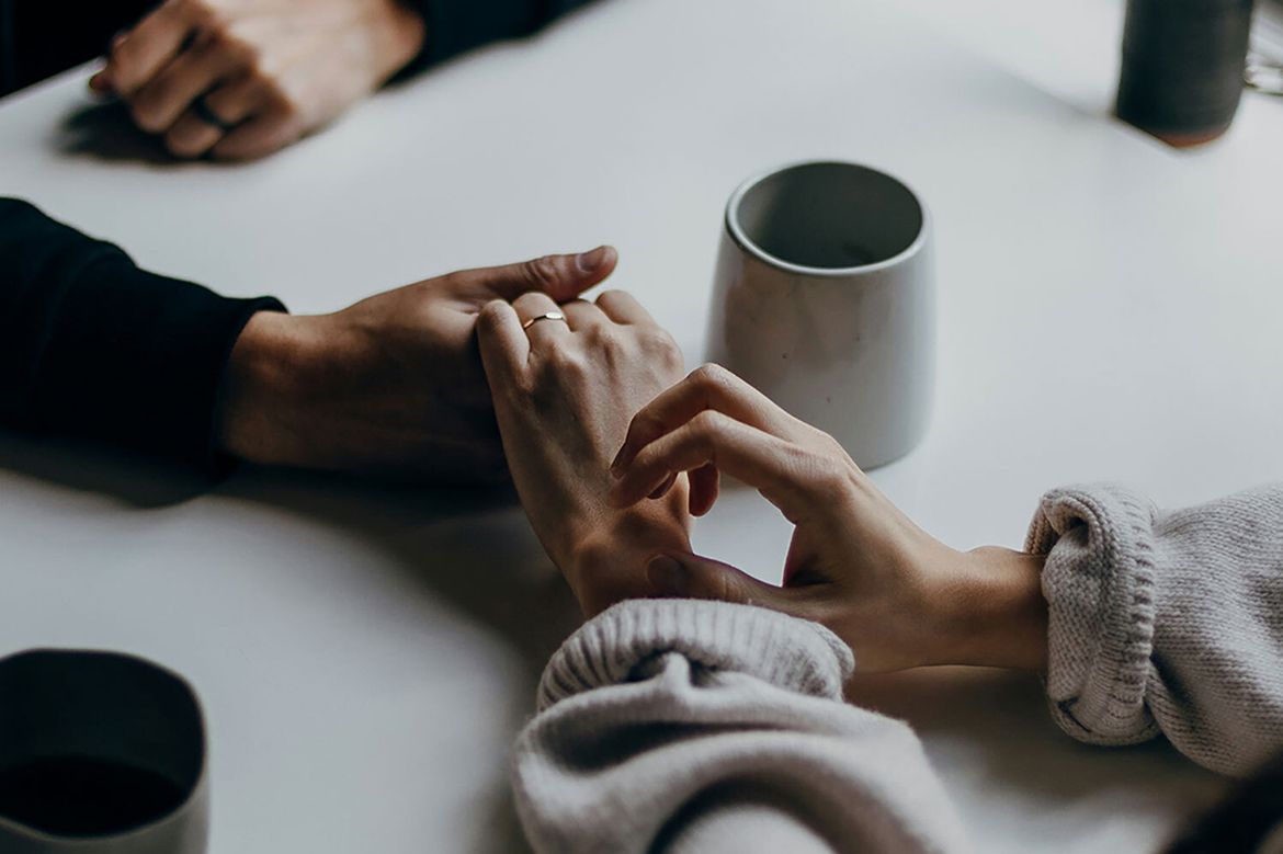 Two people hold hands atop a table