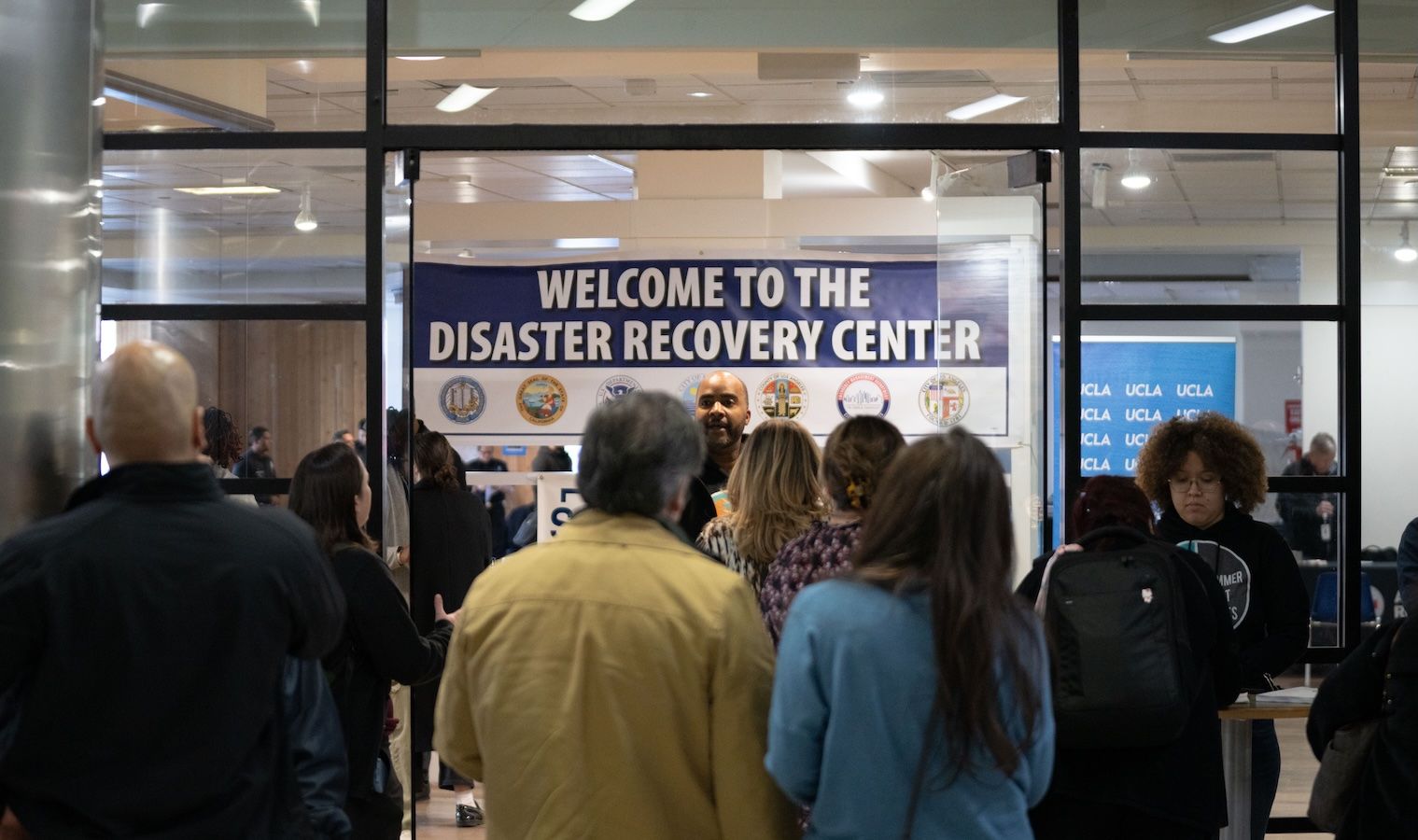 People gathered with inside UCLA Research Park with disaster recovery center sign in background