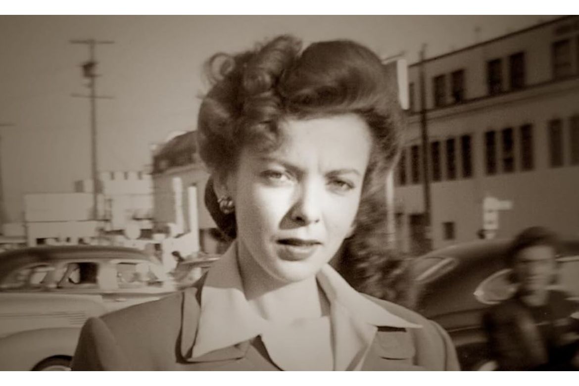 Black-and-white head-and-shoulders shot of Ida Lupino with classic cars in the background