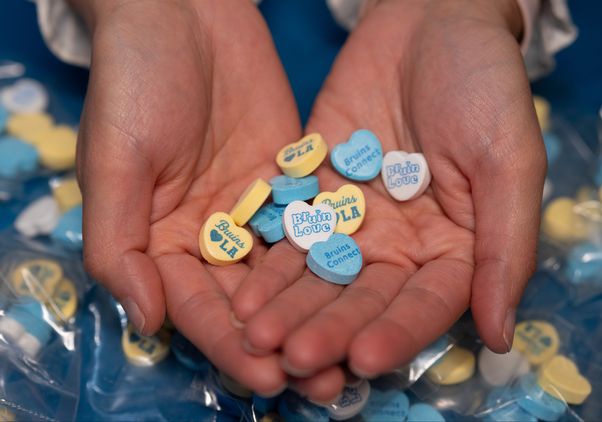 Conversation hearts in blue, yellow and white in a pair of hands