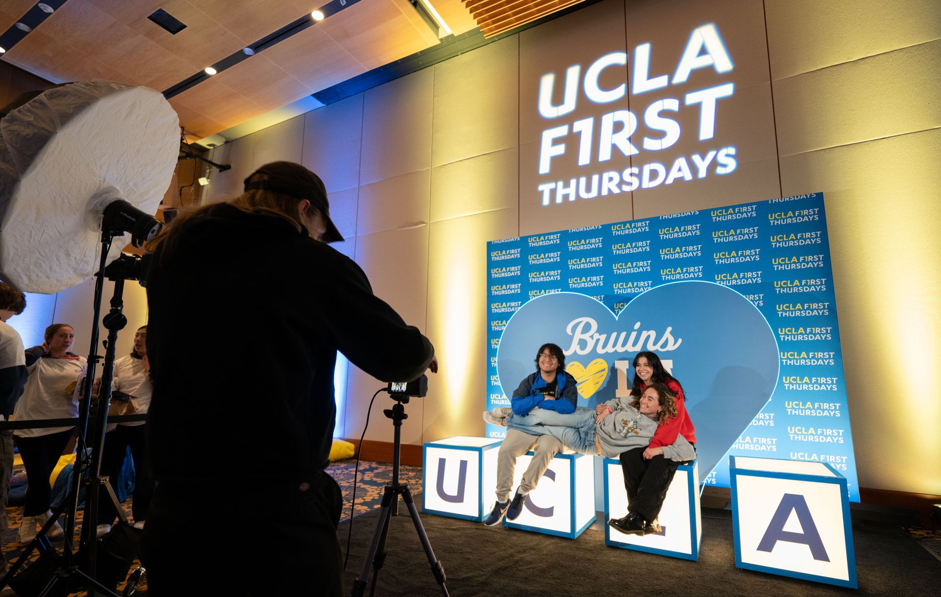 Three people pose for a photo on blocks bearing the letters UCLA