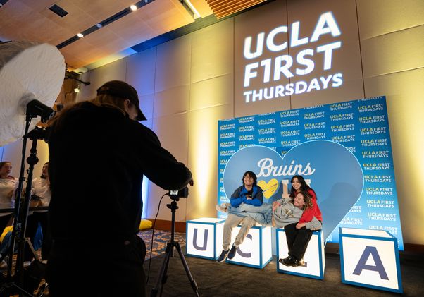 Three people pose for a photo on blocks bearing the letters UCLA