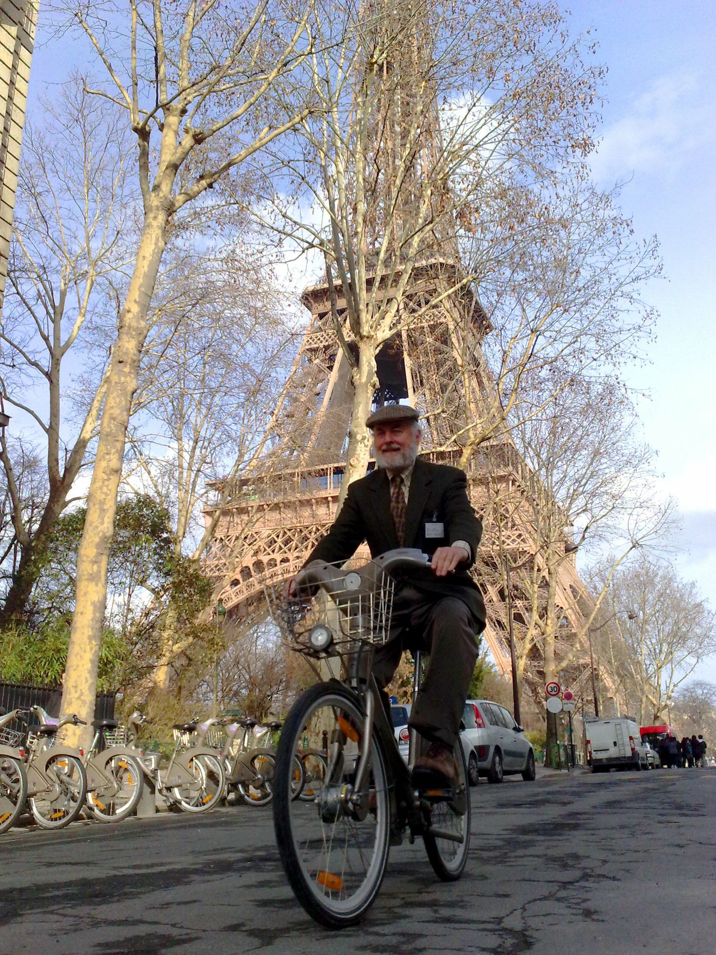 Donald Shoup rides a bicycle past the Eiffel Tower in Paris