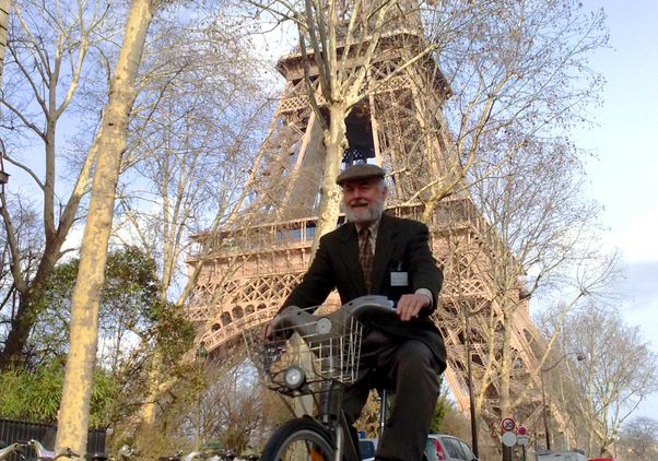Donald Shoup rides a bicycle past the Eiffel Tower in Paris