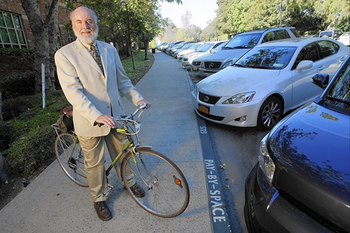 Donald Shoup — on a bicycle near parked cars on the UCLA campus