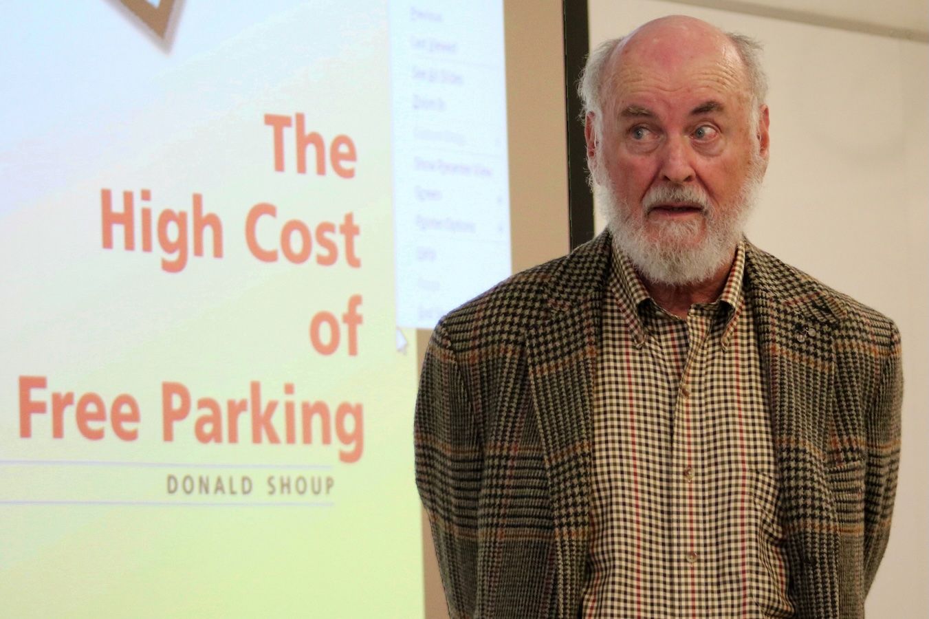Donald Shoup — standing next to “The High Cost of Free Parking” banner