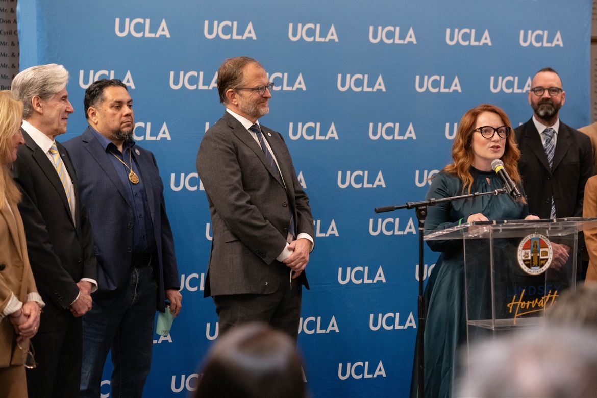 UCLA Chancellor Julio Frenk watches as County Supervisor Lindsey Horvath speaks at the podium