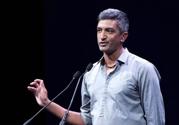 Ramesh Srinivasan, in gray top, gestures with his right hand while speaking into microphones