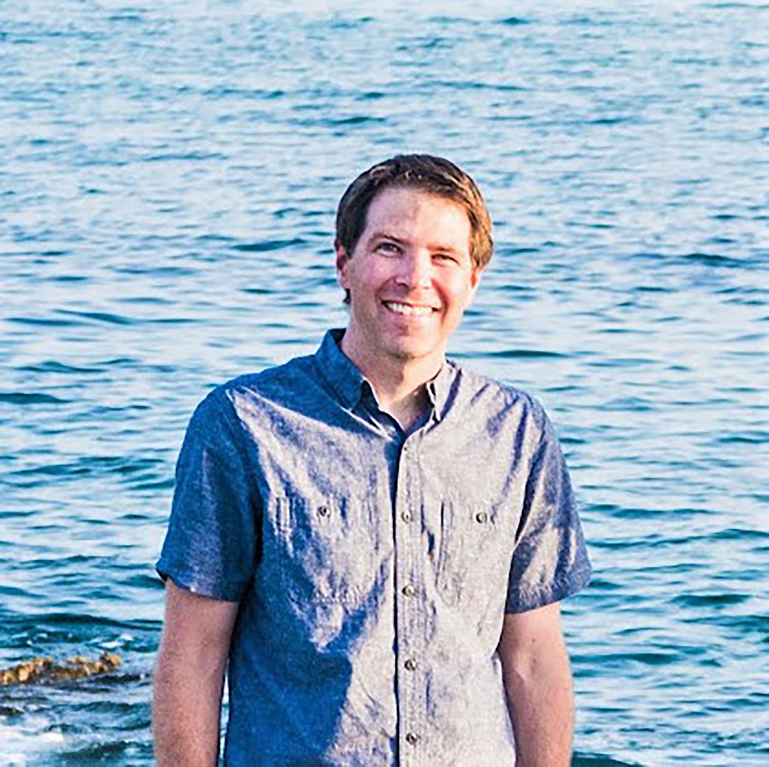 Steven Furlanetto, in blue short-sleeved shirt, with ocean behind him