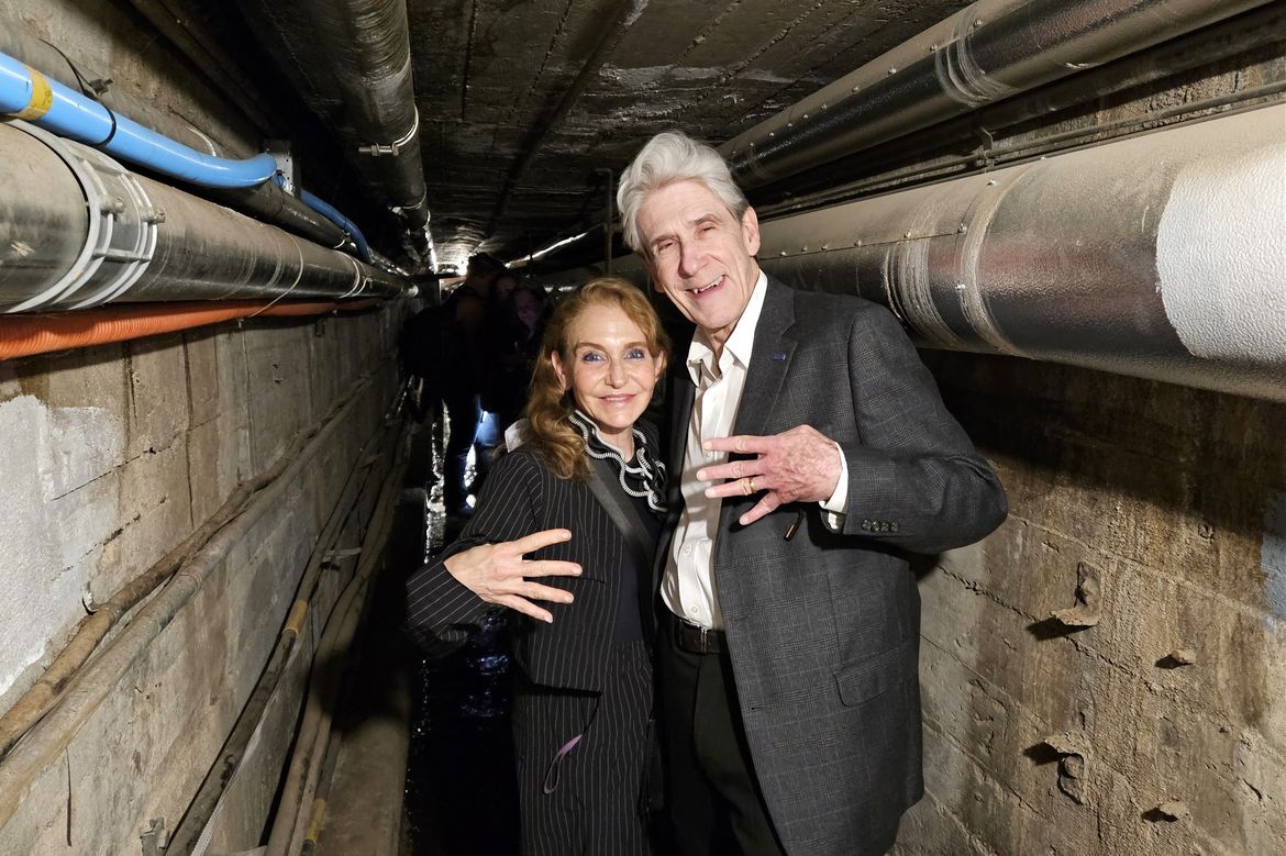 From left: Felicia Knaul, in black-and-white pinstripe suit, and Julio Frenk, in gray jacket and white button-down, making the "fours up" hand gesture
