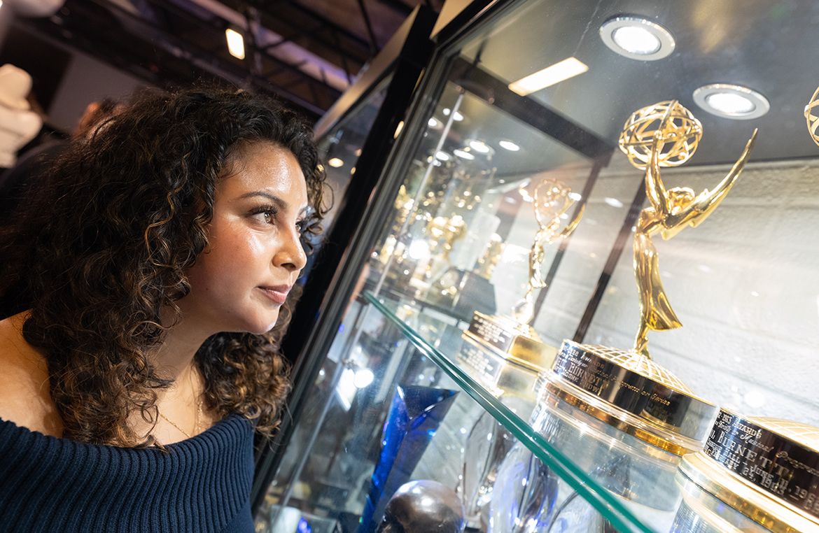 UCLA student Alexa Cruz, inaugural Carol Burnett scholarship recipient, gazes into a glass display case at Carol Burnett's Emmy Award statuettes and other trophies donated to UCLA.