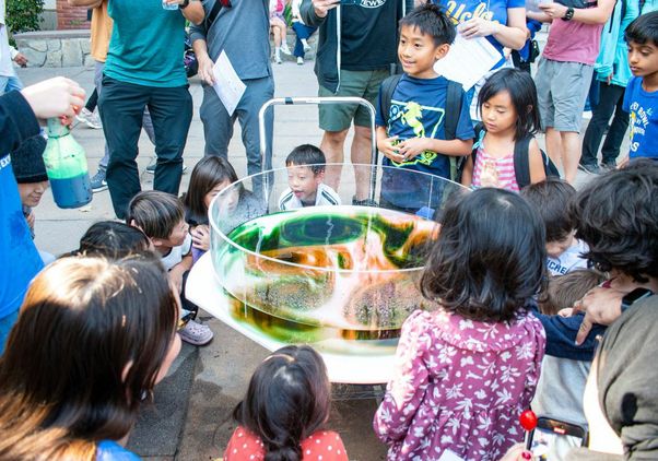 Exploring Your Universe 2025: Kids surround clear science experiment