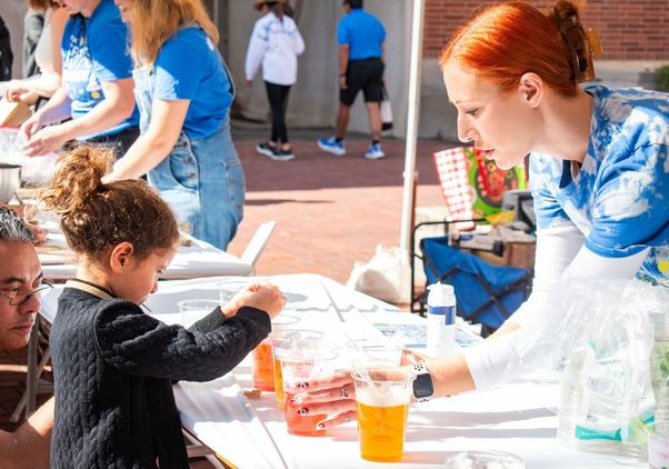 Exploring Your Universe 2025: Volunteer holds cup for young girl to play