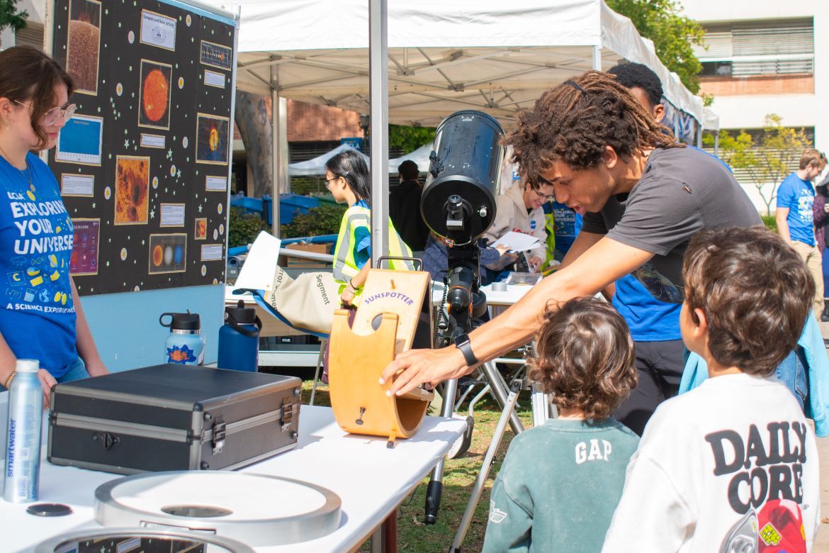 Exploring Your Universe 2025: Two kids are shown an experiment next to a telescope