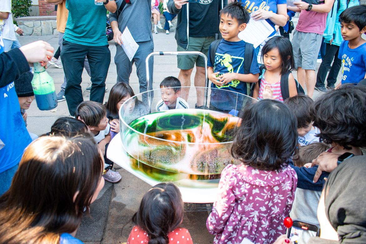 Exploring Your Universe 2025: Kids surround clear science experiment