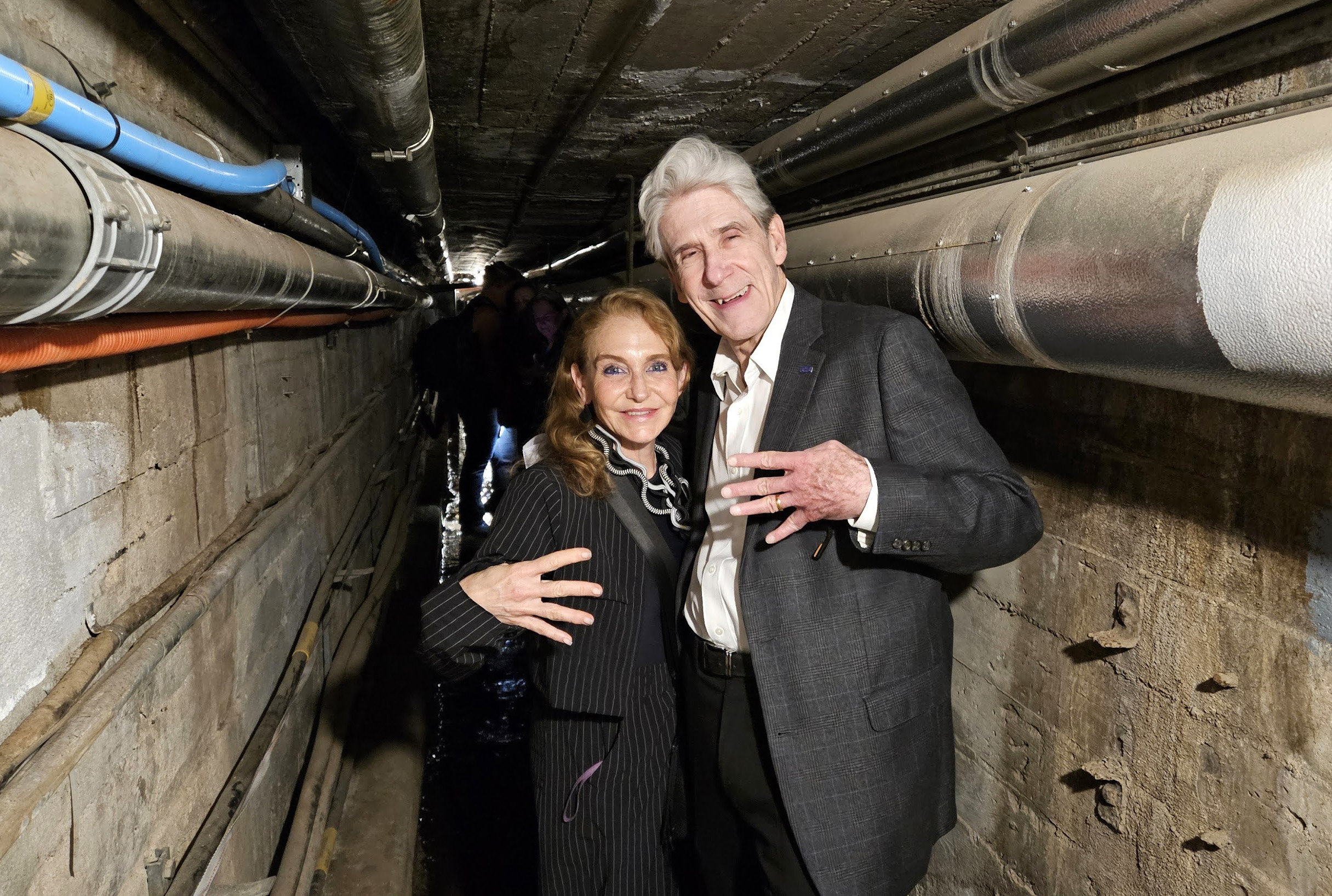 From left: Felicia Knaul, in black-and-white pinstripe suit, and Julio Frenk, in gray jacket and white button-down, making the "fours up" hand gesture