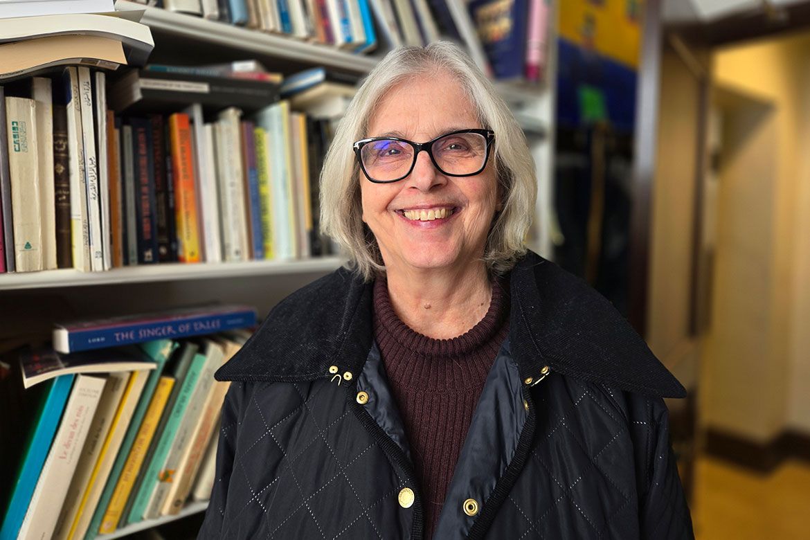 Susan Slyomovics smiles in front of a bookshelf, wearing a burgundy turtleneck sweater and a black quilted vest.