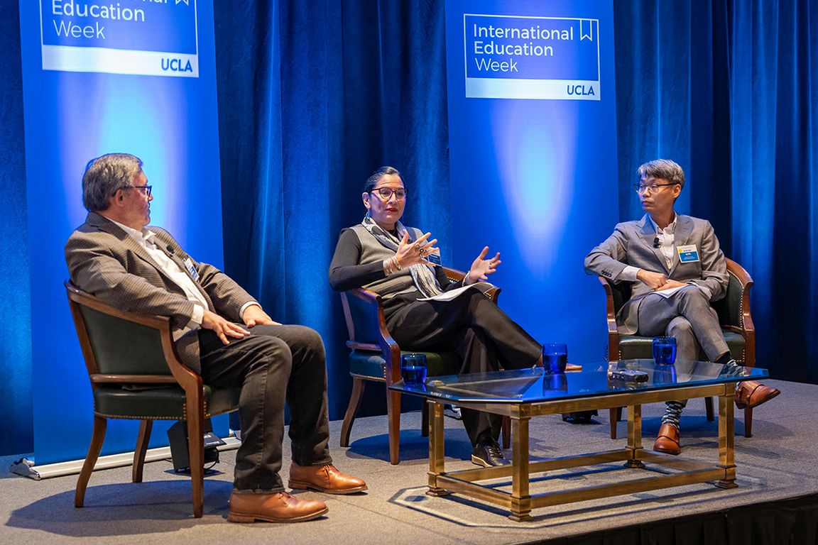 Miguel García-Garibay, Athena Jackson, and David Kim seated on stage in conversation during UCLA International Education Week. Jackson gestures while speaking to the panel.
